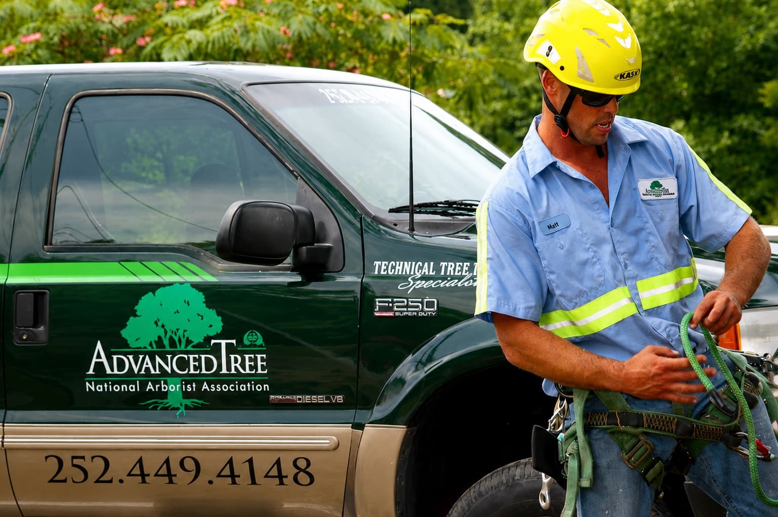 Advanced Tree arborist preparing equipment beside a branded service truck