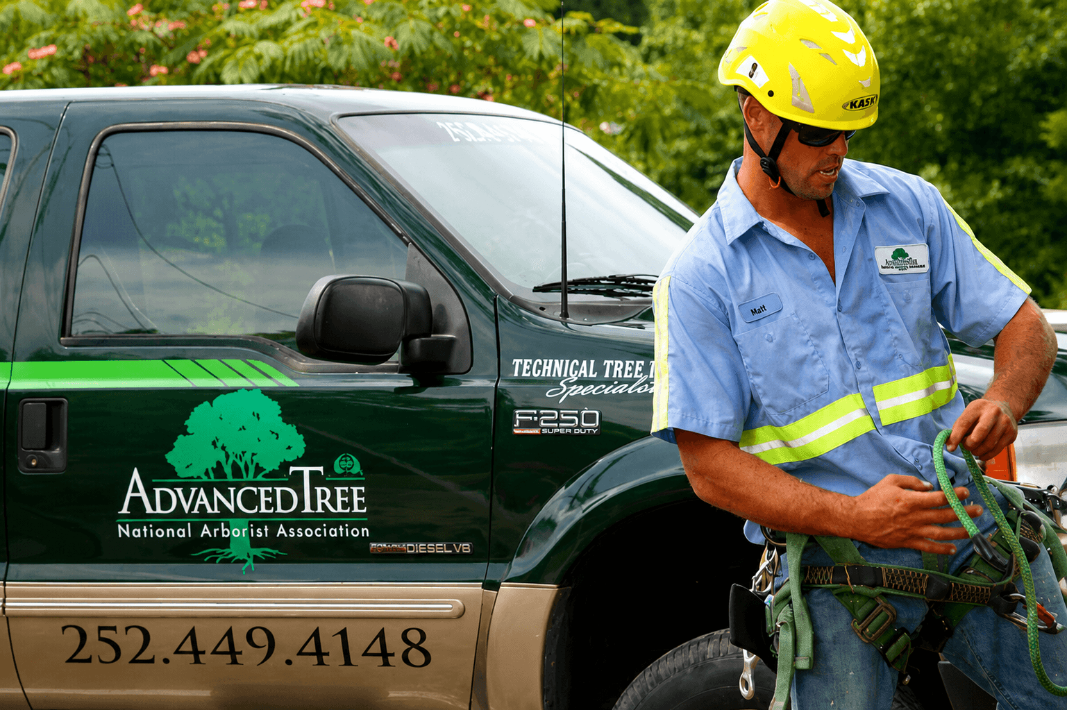 Advanced Tree arborist preparing climbing equipment beside a company truck